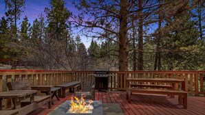 Une terrasse avec des bancs en bois, un foyer et un barbecue.