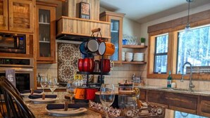 Una cucina con piano di lavoro in granito, mobili in legno e rastrelliera per pentole a sospensione.