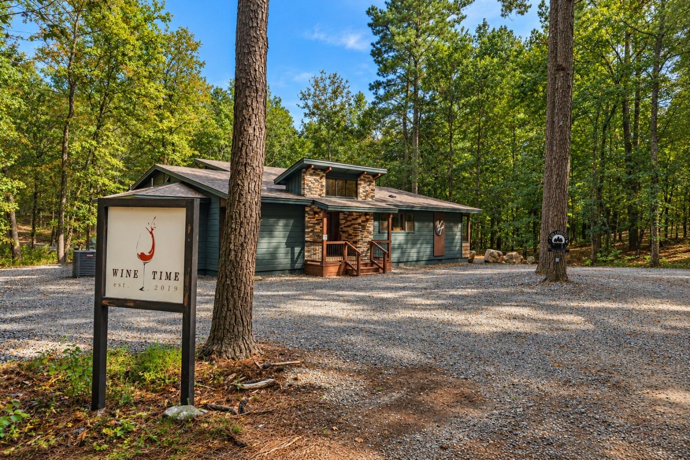 A rustic lodge with a stone and wood exterior, a gravel driveway, and a sign indicating the establishment year.