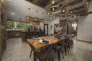 Un comedor amplio con una larga mesa de madera, múltiples sillas y una lámpara moderna.