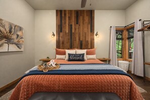 Une chambre à coucher avec une tête de lit en bois, un lit avec une literie orange, une table de chevet avec une lampe et une fenêtre avec des rideaux.