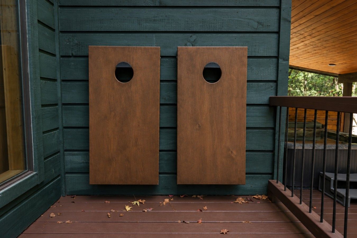 A wooden deck with two square planters against a green wall.