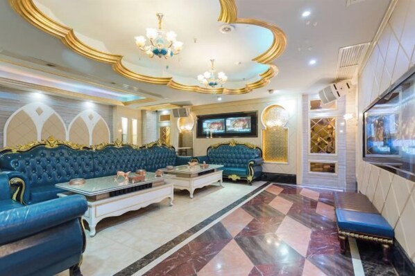 A luxurious room with a blue sofa set, a coffee table, and a television. - Xindi International Hotel (Huizhou)