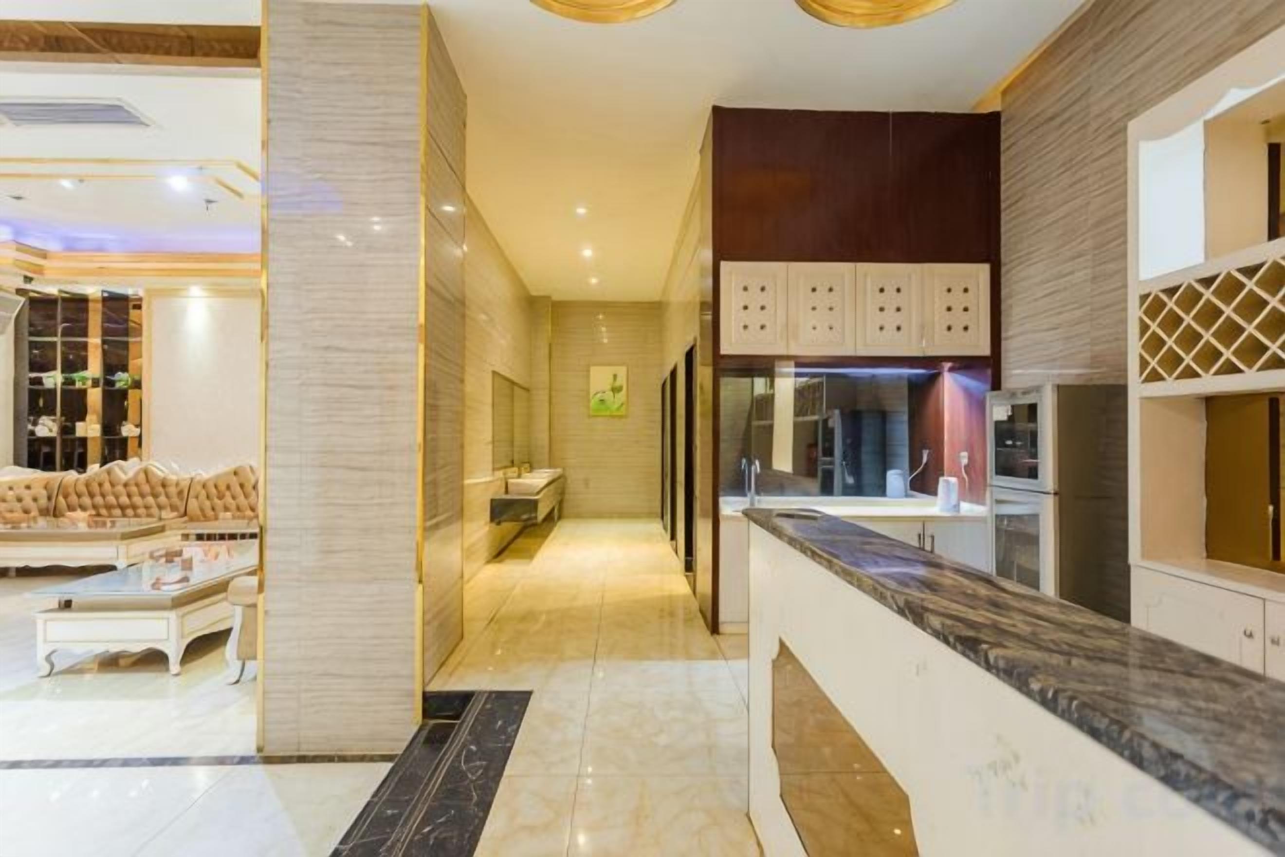 Um hall de hotel com piso de mármore, balcão de recepção e área de estar com sofás.