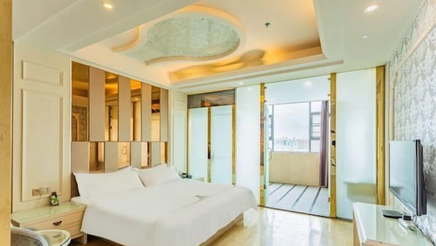 A modern hotel room with a large bed, a desk, and a TV. - Xindi International Hotel (Huizhou)