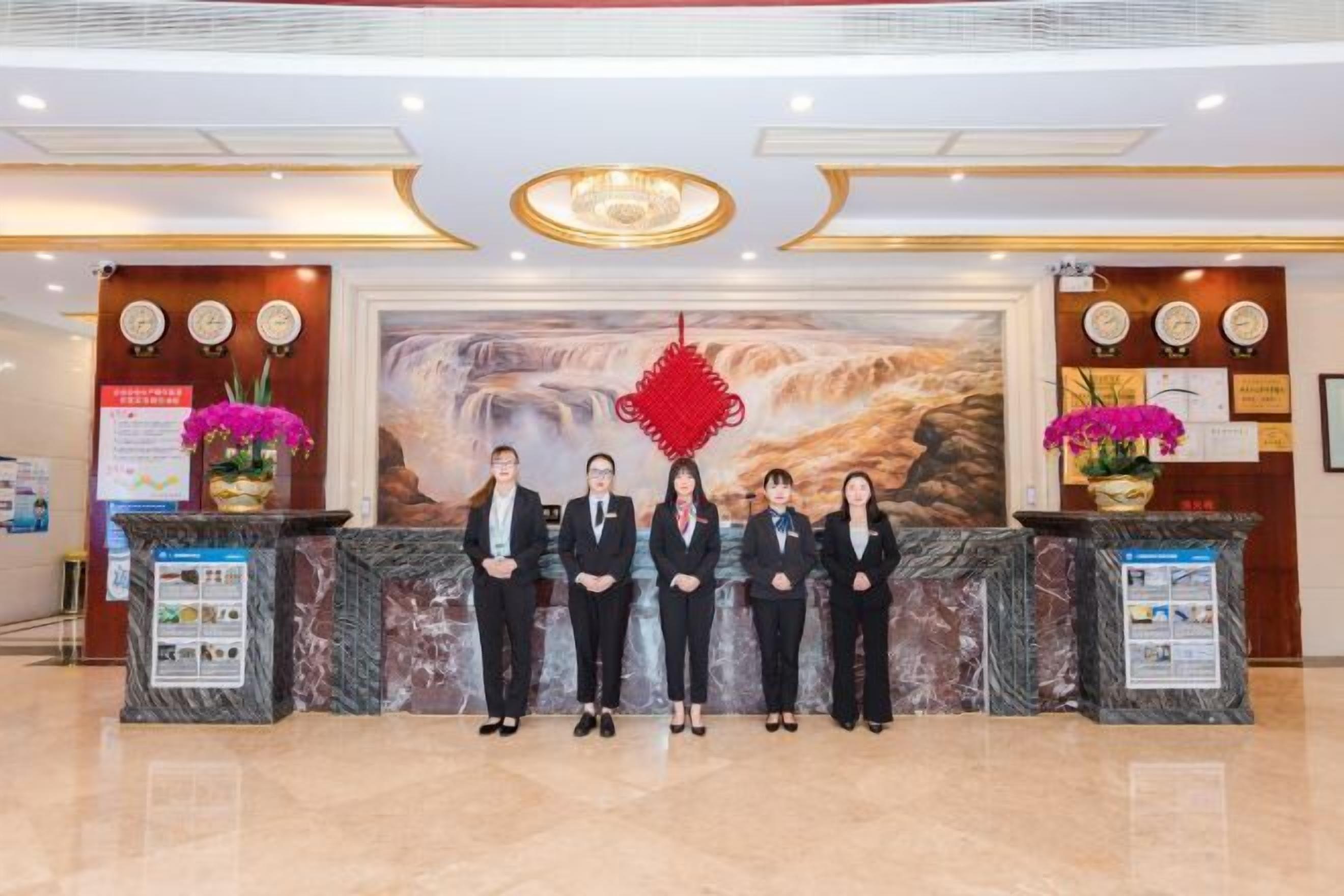 A reception area with marble counters, a large mural, and decorative elements like flowers and clocks.