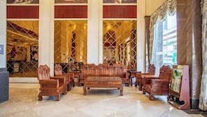 A lobby with wooden furniture, large windows, and artwork on the walls. - Xindi International Hotel (Huizhou)
