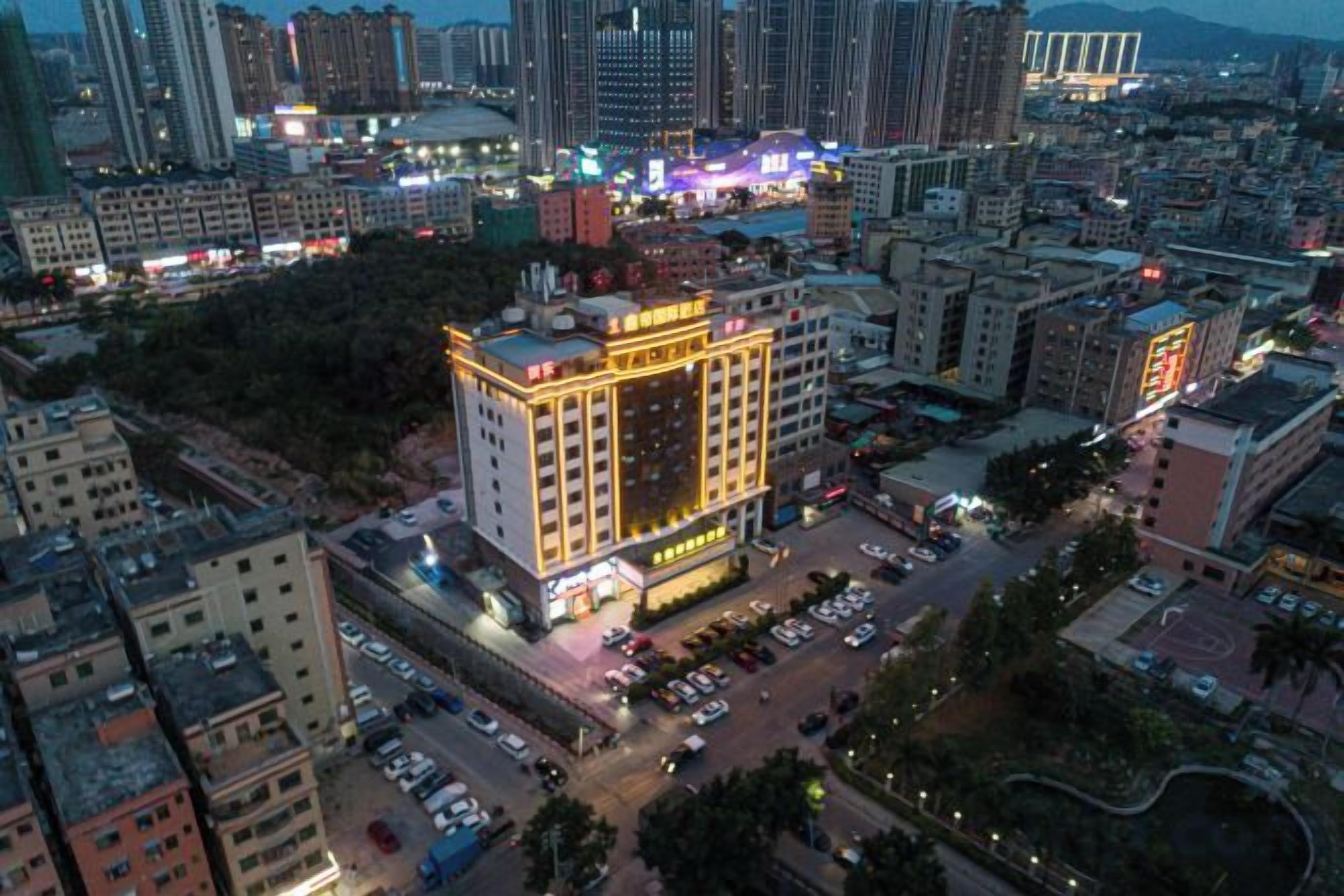 A multi-story hotel with a central courtyard, surrounded by other buildings.