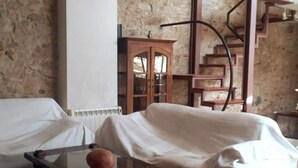 A room with a covered sofa, a glass coffee table, a wooden cabinet, and a spiral staircase. - Duplex (Lloret de Mar)