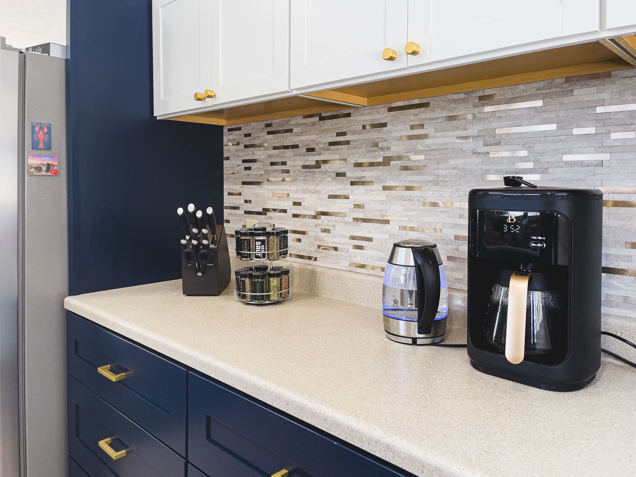 A kitchen with a coffee maker, a kettle, and a spice rack.