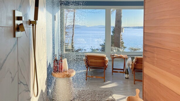 A modern bathroom with a glass-enclosed shower, wooden furniture, and a view of a snowy landscape. - Lucky Stone Retreat - Private Beach & Acadia View (Sullivan)