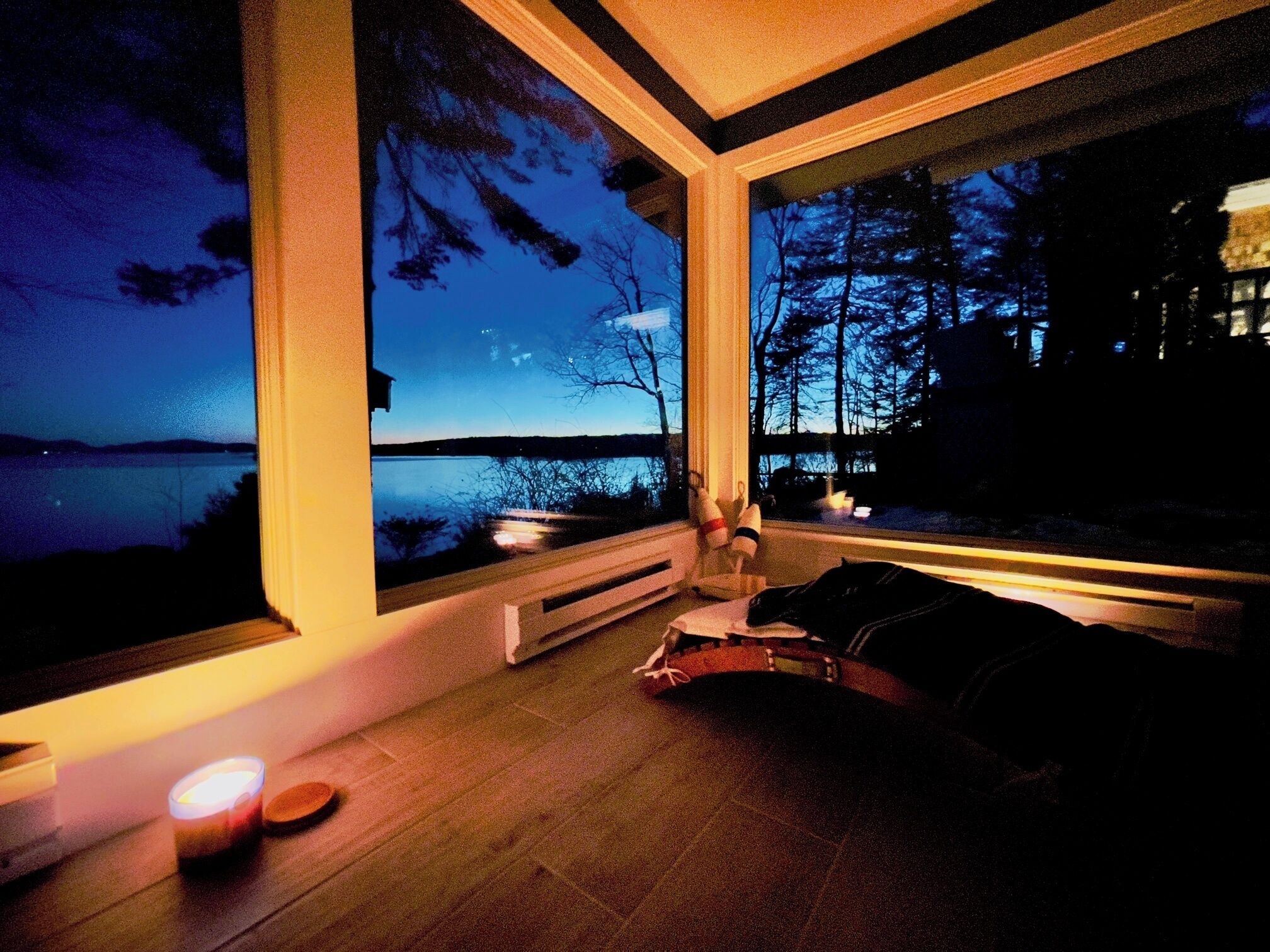 Ein modernes Zimmer mit großen Fenstern und Blick auf einen See im Abenddämmerung.