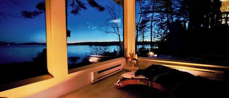 Ein modernes Zimmer mit großen Fenstern und Blick auf einen See im Abenddämmerung.