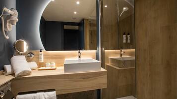Un baño moderno con un espejo grande, un secador de pelo, un lavabo y una zona de ducha.