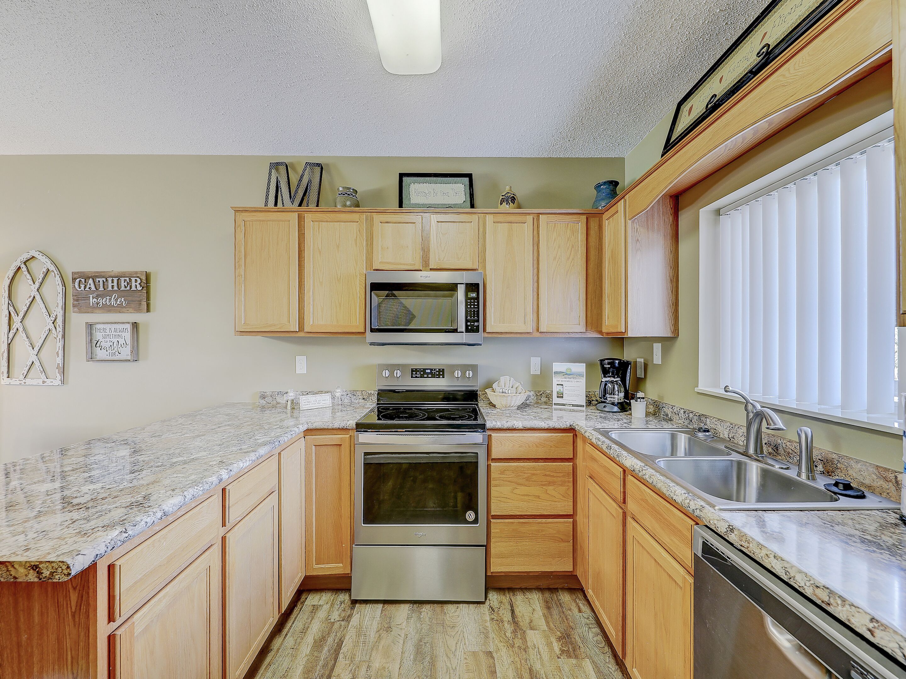 A kitchen with wooden cabinets, a microwave, an oven, and a sink.