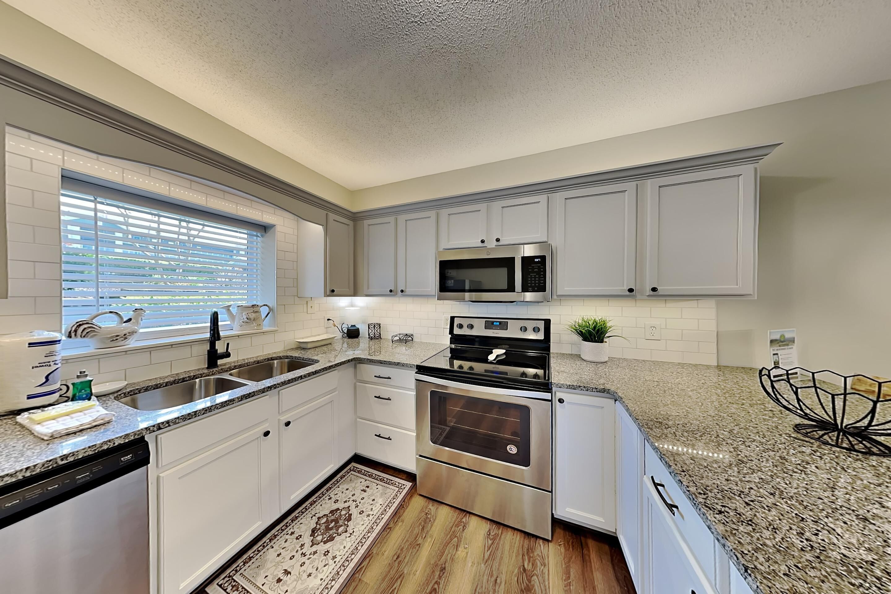 A modern kitchen with white cabinets, stainless steel appliances, and a granite countertop.