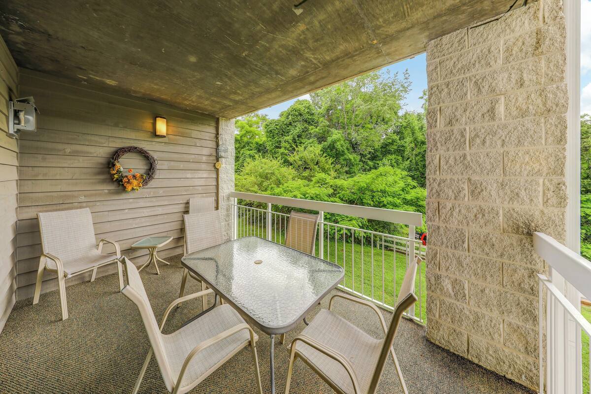 A covered patio with a table and chairs, a decorative wreath, and a view of greenery.