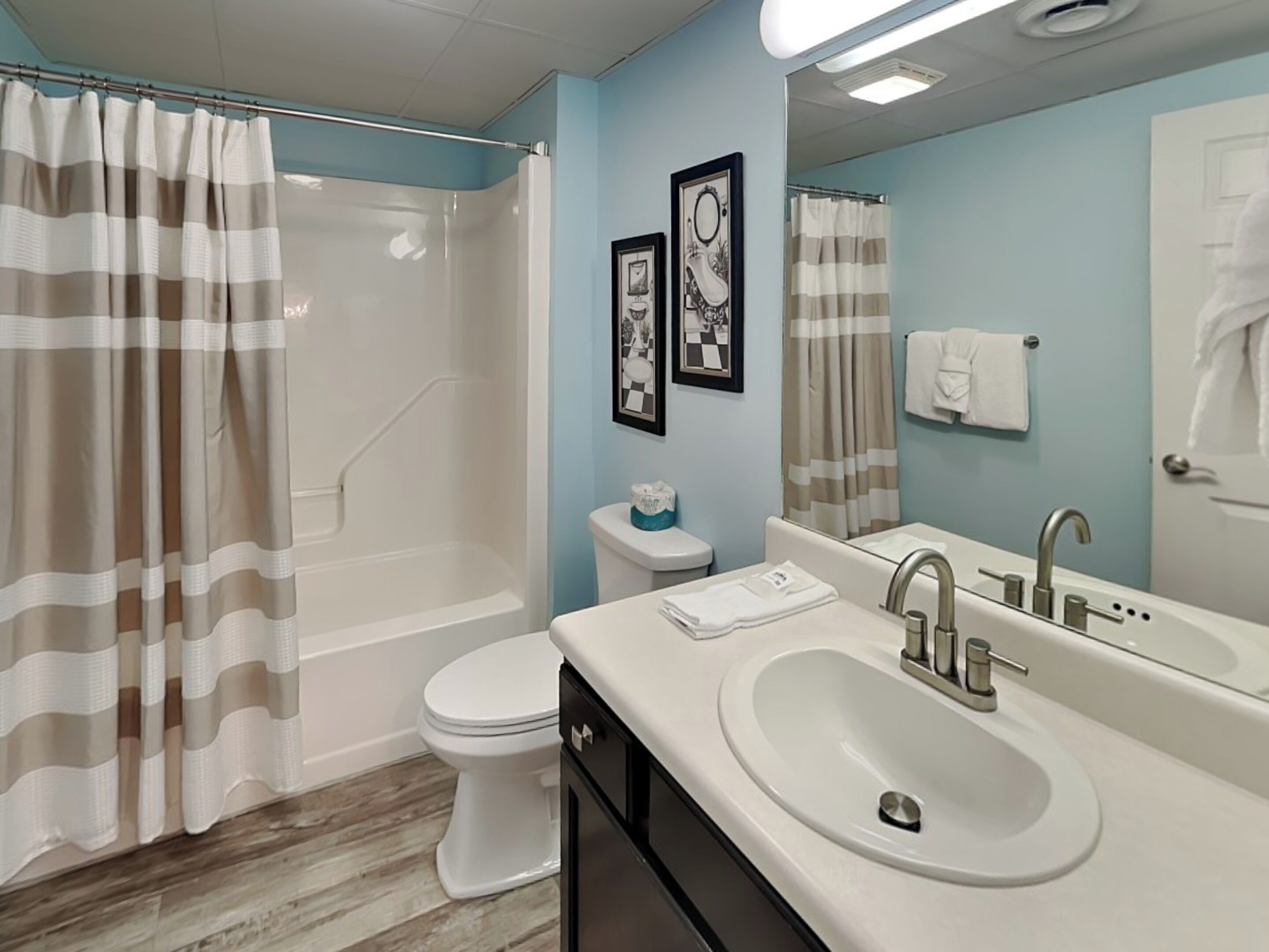 A bathroom with a shower, toilet, sink, and a mirror.