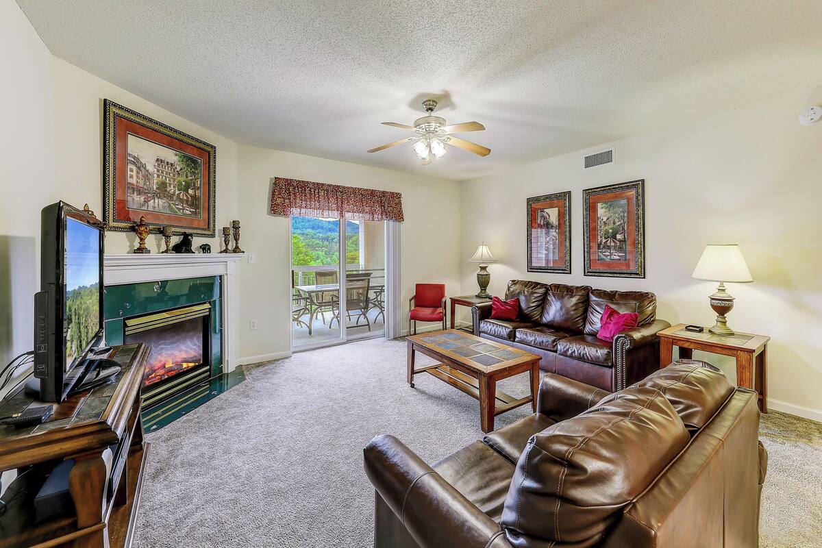 A living room with a fireplace, leather sofa, and a television.