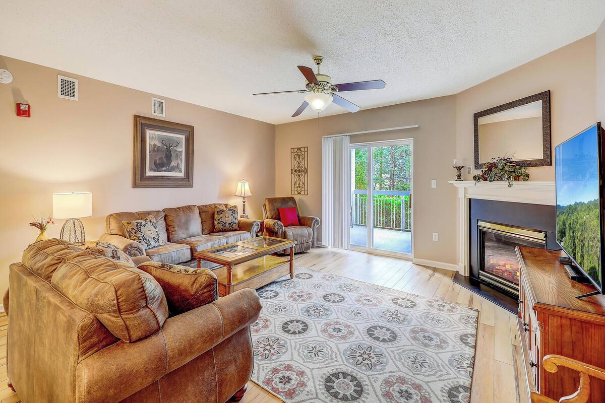 A living room with a sofa, armchairs, a coffee table, and a fireplace.