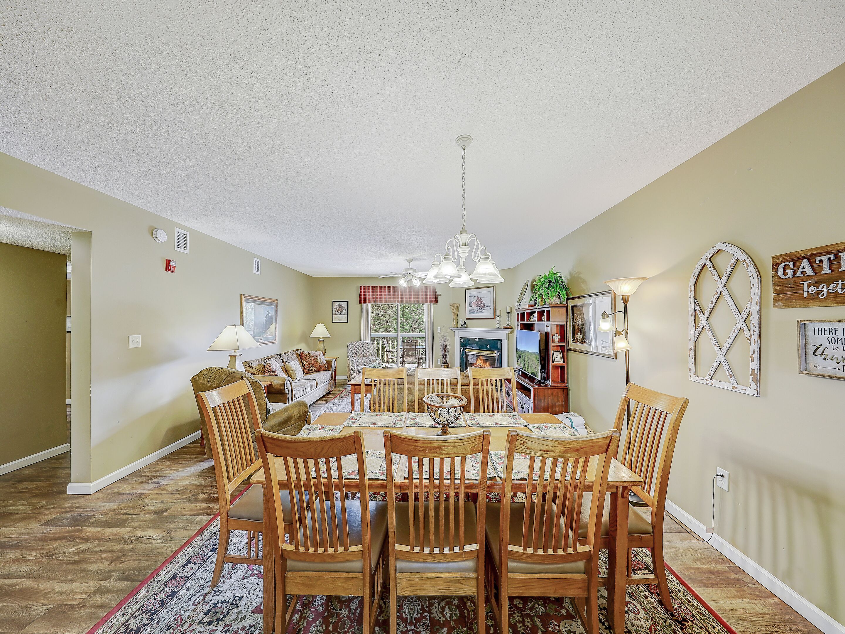 A dining area with a wooden table and chairs, a chandelier, and a fireplace.