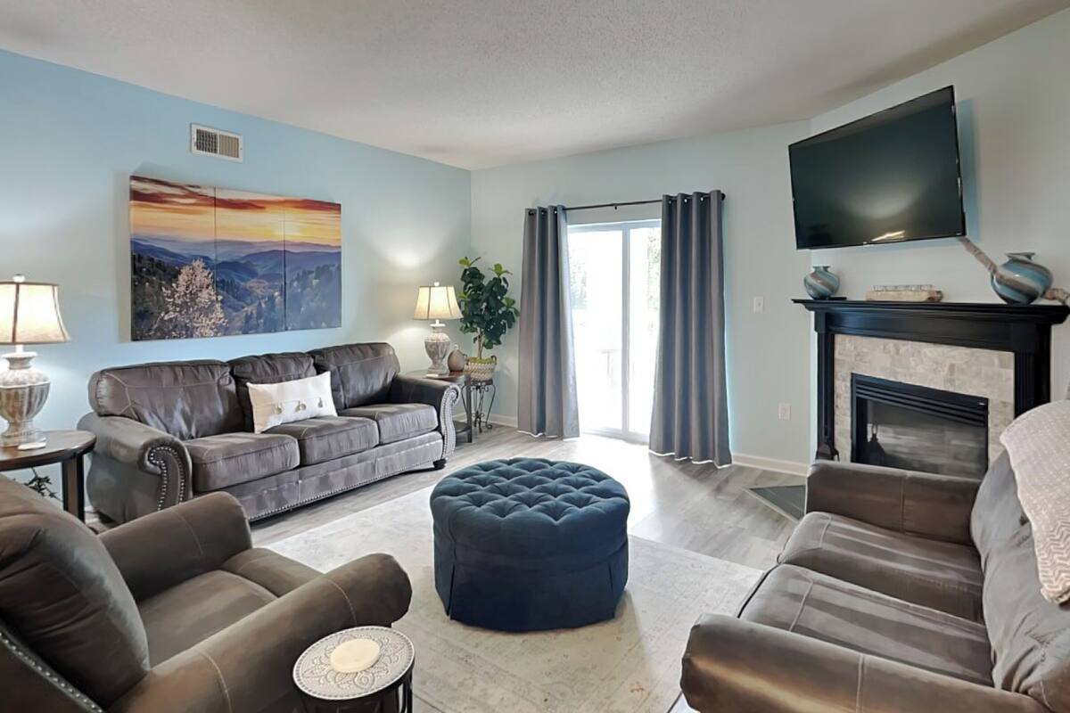 A living room with a fireplace, a large flat-screen TV, and a sofa set.