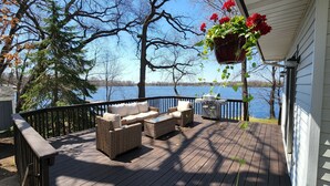 A wooden deck with wicker furniture and a hanging flower pot.