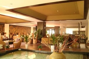 Un lobby espacioso con una fuente central, zonas de estar cómodas y un diseño de interiores moderno.