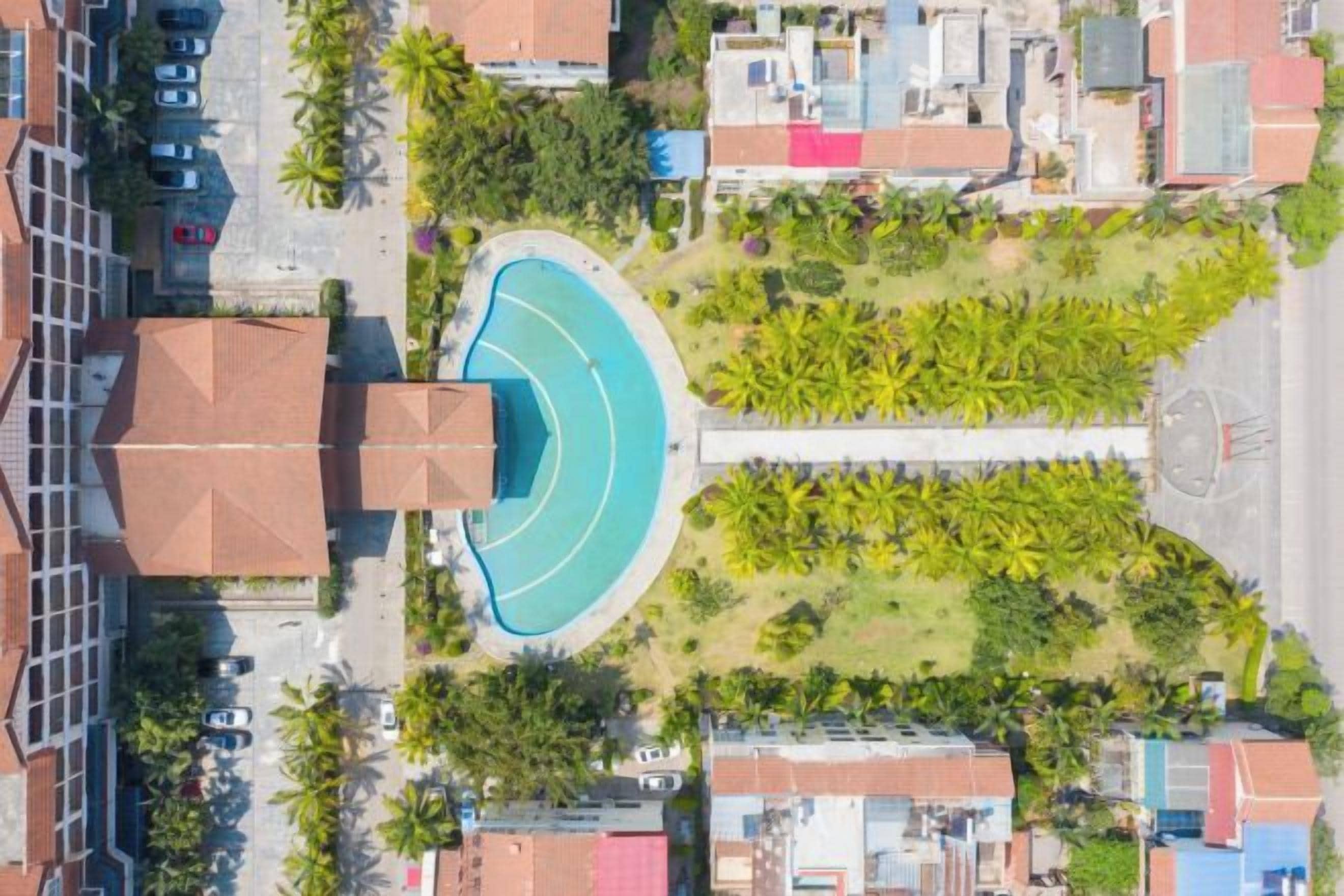 Vista aérea de una zona residencial con piscina, un monumento central y vegetación circundante.