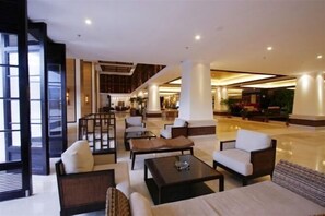 A spacious lobby with seating areas, a staircase, and a view of the interior.