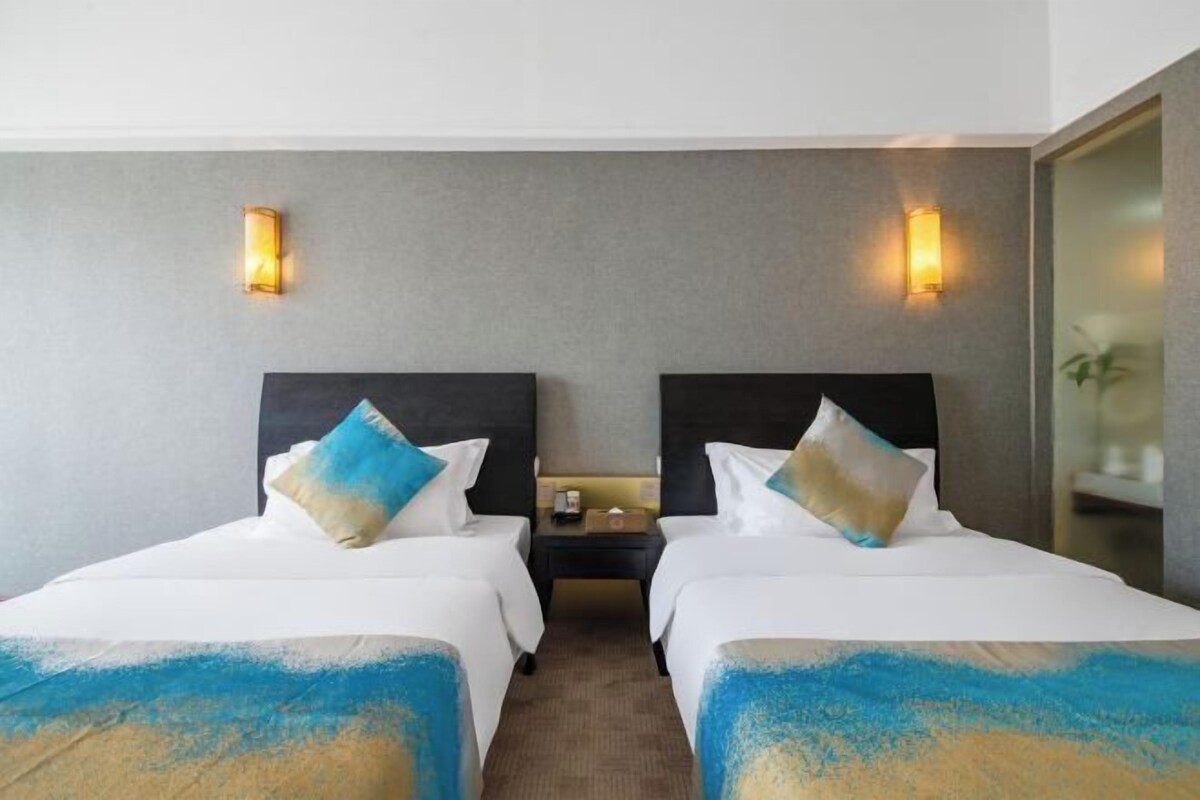 Une chambre d’hôtel avec deux lits, une table de chevet et des lampes fixées au mur.