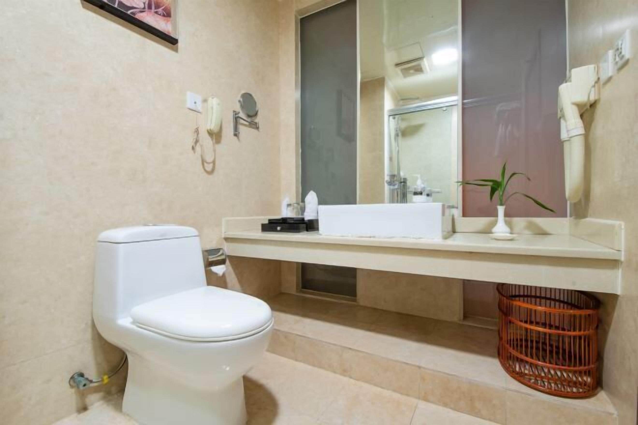 A bathroom with a toilet, sink, mirror, and a basket.