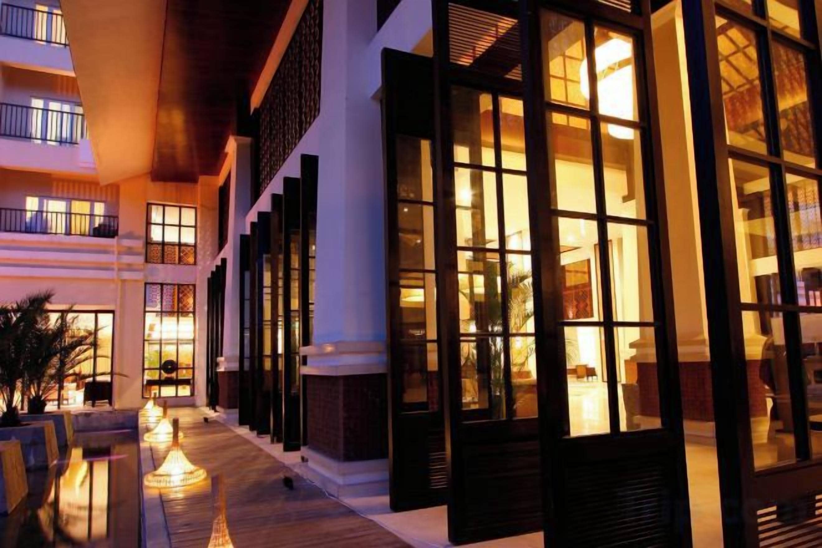 A hotel with multiple floors, large windows, and a well-lit exterior.