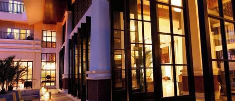 A hotel with multiple floors, large windows, and a well-lit exterior.