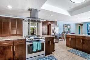 Enjoy cooking in this well-lit kitchen with a central island, stainless steel range, and large window offering a view of the outdoors.