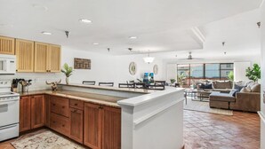 Un'ampia cucina con mobili in legno, un'isola centrale e un'area pranzo con divano e tavolino.
