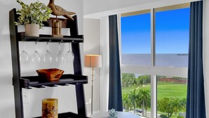 A room with a view of the sea, a black shelf with wine glasses, a lamp, and a small table. - SF Ocean View 2BD/2Bth @ Hotel IN Coconut Grove (Miami)