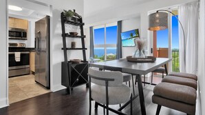 A modern kitchen with stainless steel appliances, a dining area with a view of the ocean, and a balcony with a view of the ocean. - SF Ocean View 2BD/2Bth @ Hotel IN Coconut Grove (Miami)
