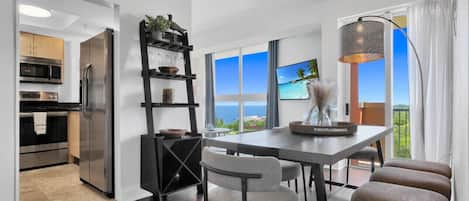 Una cocina moderna con electrodomésticos de acero inoxidable, un comedor con vistas al océano y un balcón con vistas al mar.