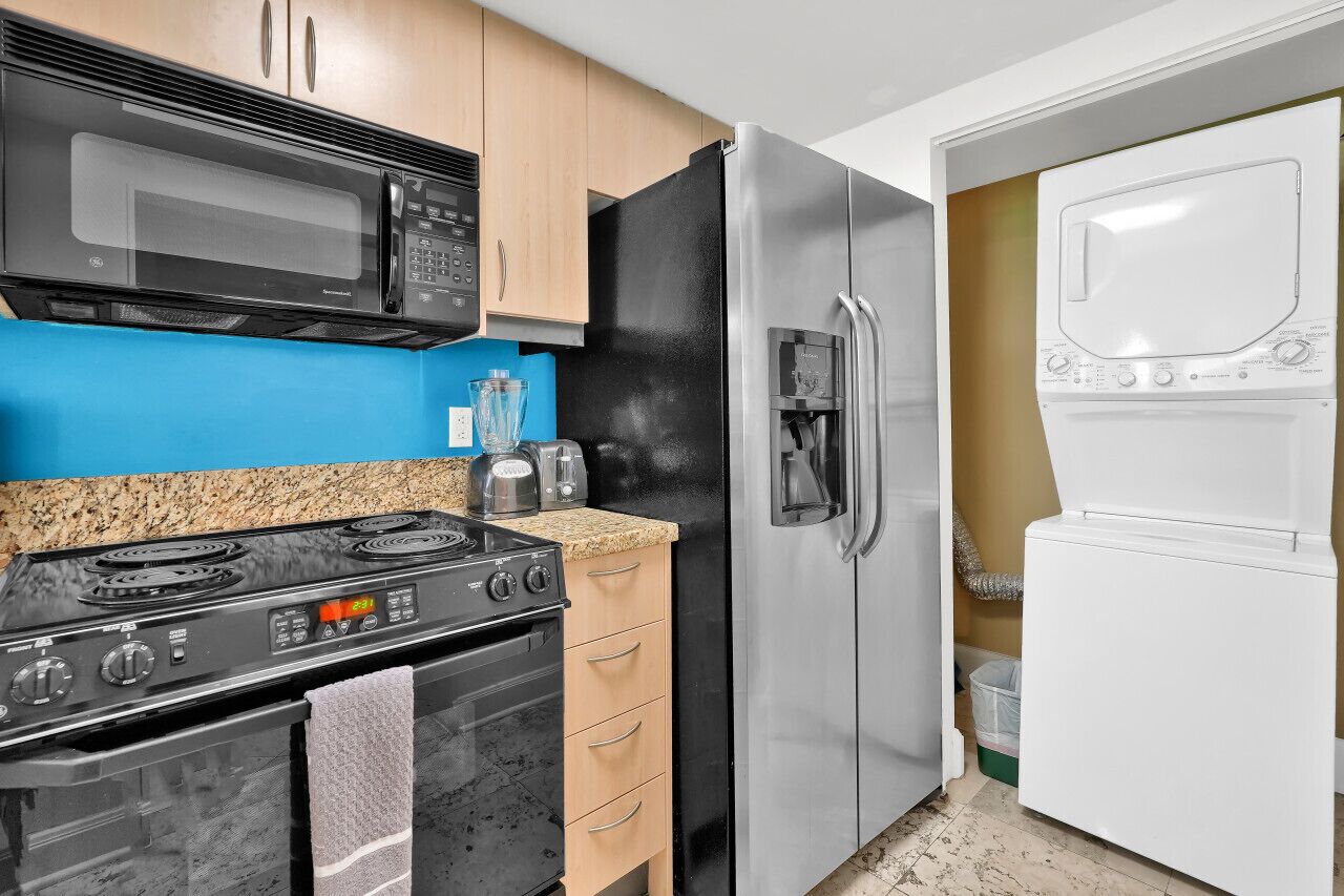 A compact kitchen with a stove, microwave, refrigerator, and built-in washer-dryer.
