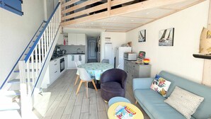 Ein kompakter Wohnraum mit Küchenzeile, Essbereich und einer Couch mit kleinem Tisch.