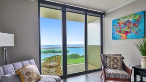 Una sala de estar moderna con un sofá, un sillón y vistas al mar a través de amplios ventanales correderos.