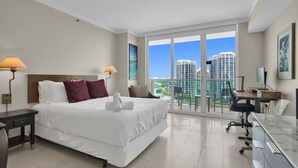 A modern hotel room with a large bed, a desk, and a balcony with a city view. - SF Amazing Studio - Walking Distance to Cocowalk (Miami)