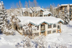 A snow-covered building with multiple balconies and large windows, surrounded by snow-laden trees. - INS02 | Amazing View | Ski In/Out | Pool/Hot Tub | Winter Shuttle | Close to Mtn (Steamboat Springs)