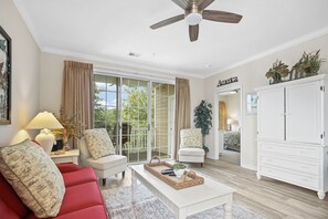 Relax in this inviting living space with a sofa, coffee table, and ceiling fan, offering a comfortable atmosphere and practical amenities.