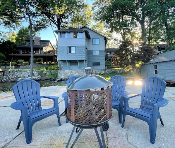 A patio with Adirondack chairs and a metal fire pit.