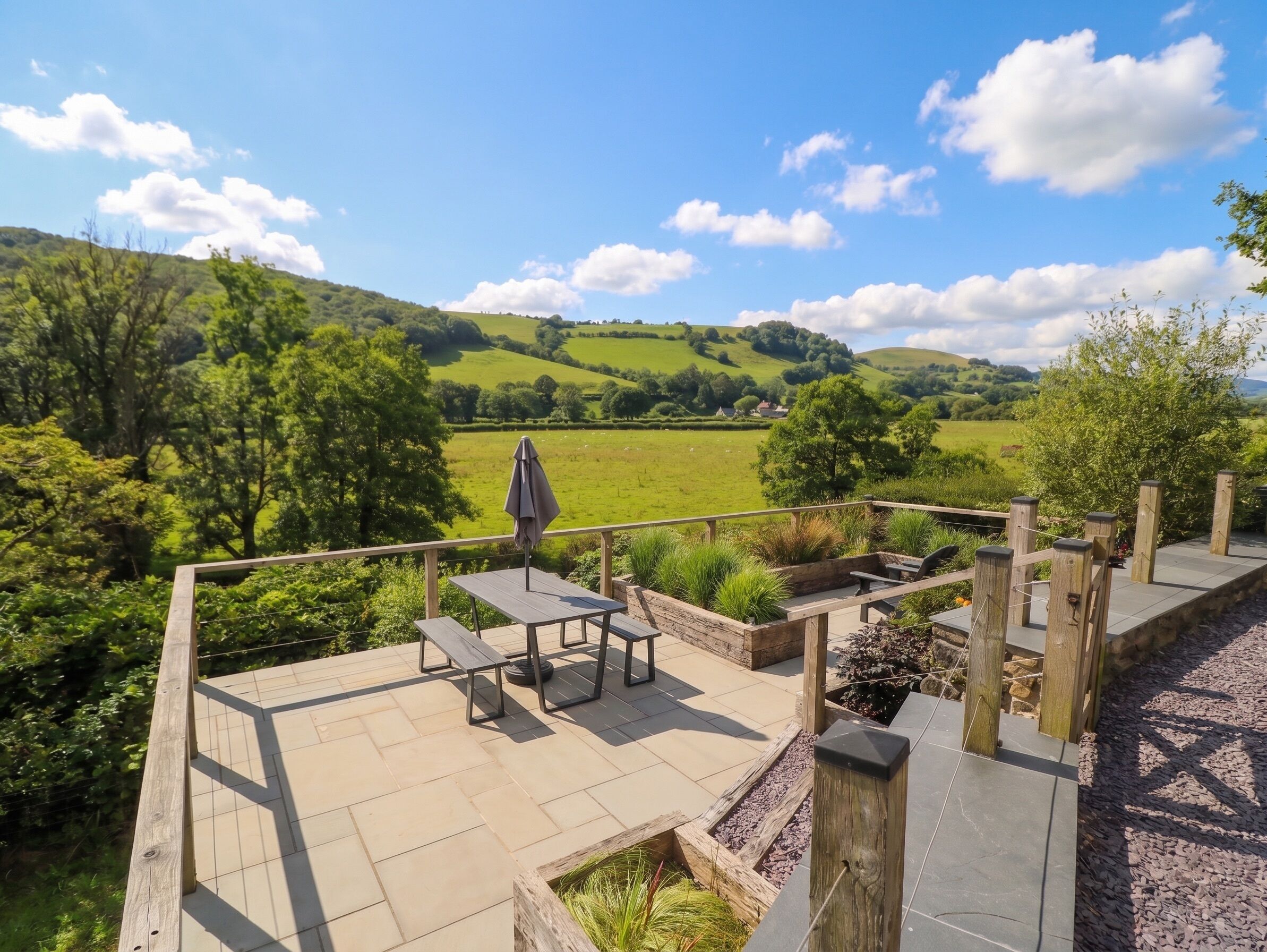 Une terrasse extérieure avec une table et des chaises, donnant sur un paysage verdoyant et vallonné.