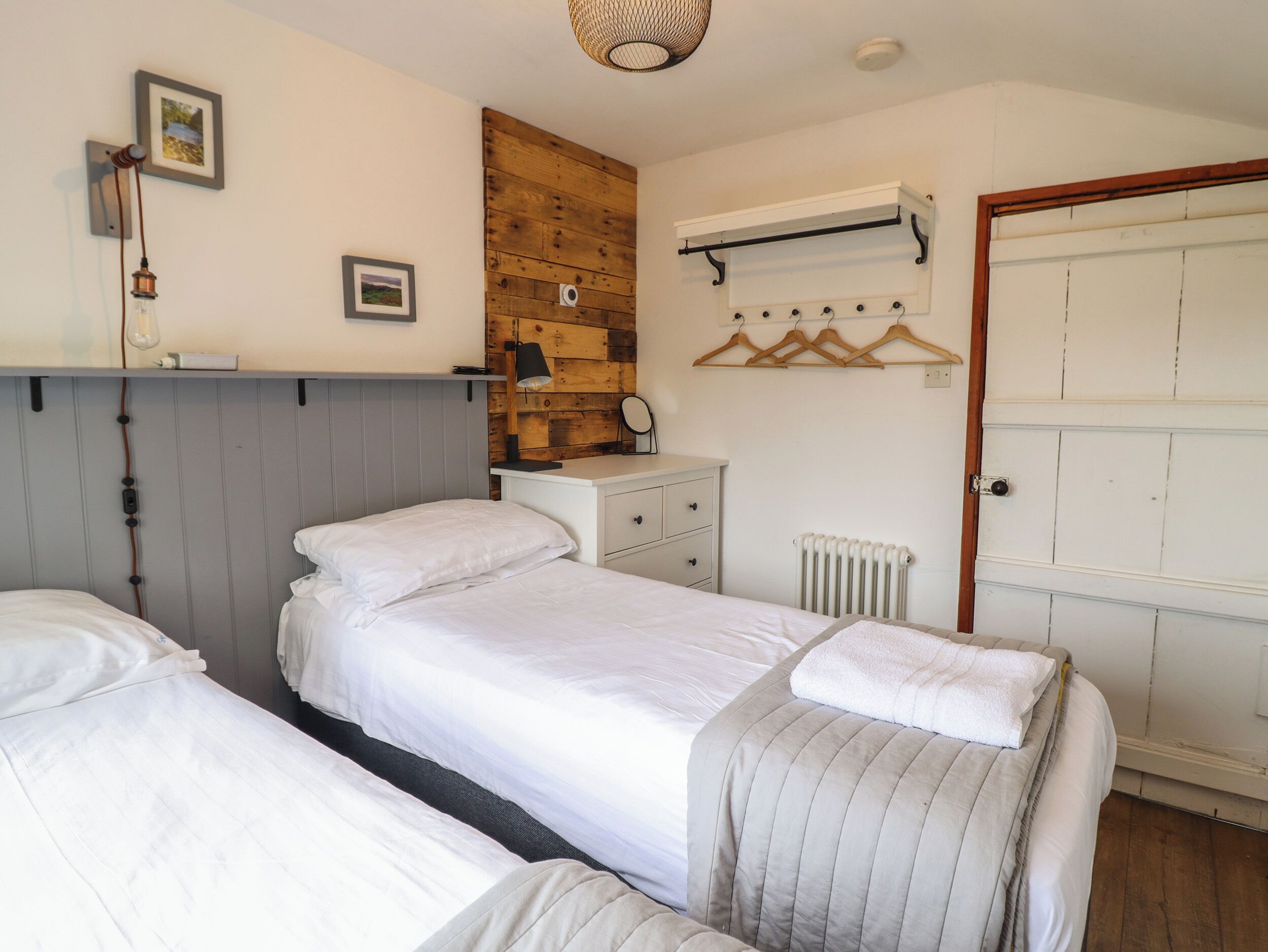 Ein Schlafzimmer mit zwei Betten, einem Schminktisch, einem Heizkörper und einer Holzwandverkleidung.