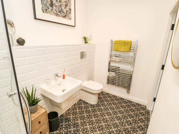 A bathroom with a white sink, toilet, and a towel rack with a yellow towel.