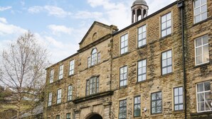 A stone building with multiple windows and an arched entrance. - Over The Arch (Keighley)
